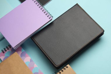 Mavi arkaplandaki yüzen not defterlerinin bileşimi