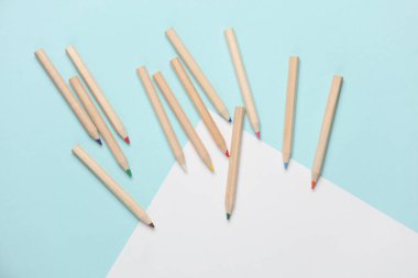 Ahşap renkli kalemler ve mavi arka planda kağıt çarşaf. Yaratıcılık, sanat