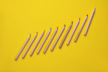 Sarı arka planda tahta renkli kalemler. Yaratıcılık, sanat