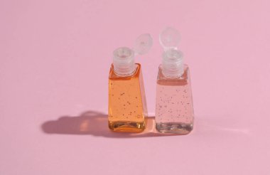Pembe arka planda gölgeli antiseptik şişeler.