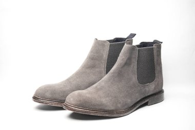 Beyaz arka planda gri süet Chelsea çizmeleri.