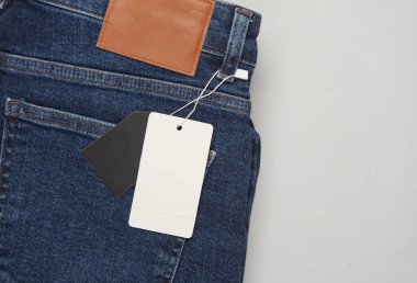 Gri arka planda beyaz etiketli mavi kot pantolon