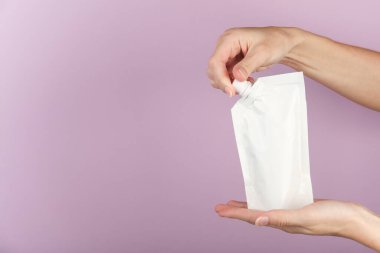 Eller koyu gri arka planda şeker kutusuyla birlikte beyaz doy paketini açın. Tasarım için şablon, model