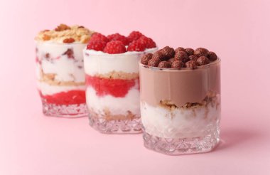Cam bardaklarda ev yapımı tatlılar yoğurt, böğürtlen ve pembe arka planda çikolata.