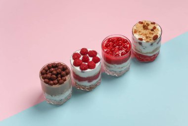 Yoğurt, böğürtlen, kurabiye ve pembe mavi arka planda çikolata toplarıyla dolu cam bardaklarda ev yapımı tatlılar..