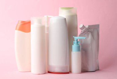 Pembe arka planda birçok farklı şampuan ve diğer kozmetik ürünler.