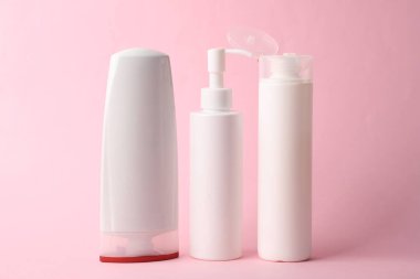 Pembe arka planda birçok farklı şampuan ve diğer kozmetik ürünler.