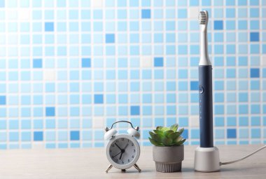 Modern akıllı ultrasonik diş fırçası, çalar saat ve masaya bitki.