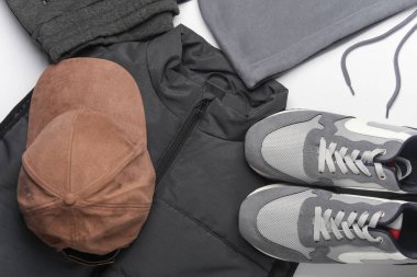 Beyaz arka planda erkek kolsuz ceketi, eşofman altı, spor ayakkabısı ve şapkası. Üst Manzara. Spor kıyafetleri..