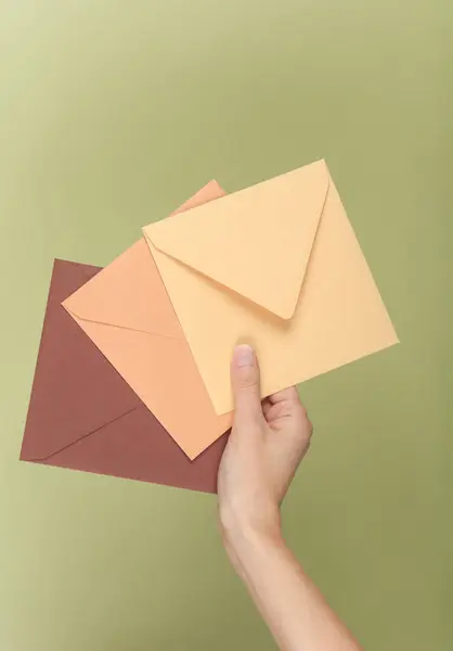 stock image Hand holding envelopes on green background