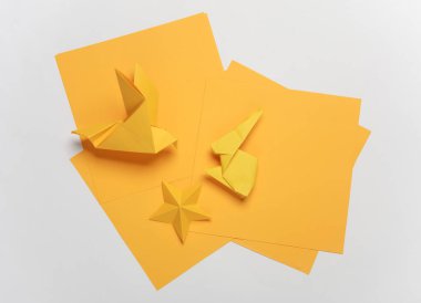 Sarı kağıt origami yıldızı, beyaz arka planda tavşan ve güvercin.