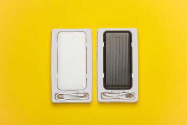 Sarı arka planda beyaz ve siyah güç bankaları. Akıllı telefon ve diğer cihazları şarj etmek için harici bataryalar. Üst görünüm