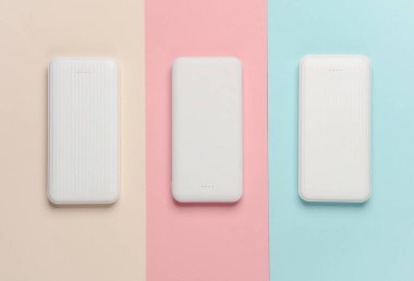 Pastel arka planda beyaz güç bankaları. Akıllı telefon ve diğer cihazları şarj etmek için harici bataryalar. Üst görünüm
