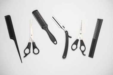 Saç kesme makası ve jilet, beyaz arka planda taraklar. Berber 'in çalışma aletleri