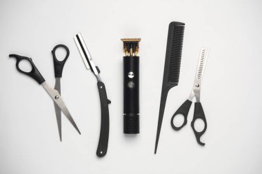 Makas, saç kesme makası ve jilet, beyaz arka planda tarak. Berberin çalışma aletleri. Üst Manzara. Düz yatıyordu