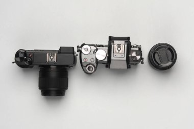 Gri arka planda lensleri olan iki modern dijital aynasız kamera. Üst görünüm