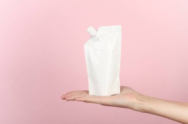 Elinde şeker kutusu olan, pembe arka planda beyaz bir köpek. Tasarım için şablon, model