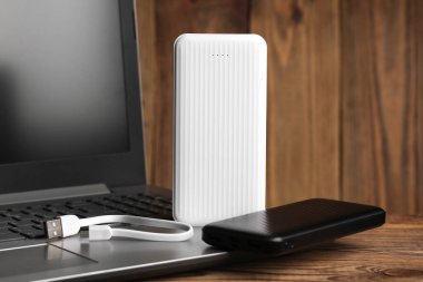 Tahta zemin üzerinde güç bankaları dış bataryası olan dizüstü bilgisayar