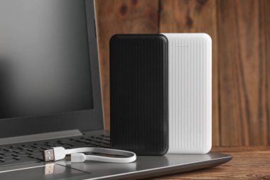 Tahta zemin üzerinde güç bankaları dış bataryası olan dizüstü bilgisayar