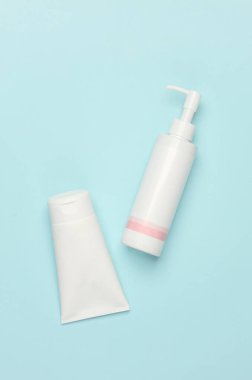 Mavi arka planda beyaz krema şişeleri. Kozmetik