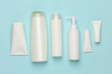 Mavi arka planda kozmetik tüpleri, şişeler ve kavanozlar