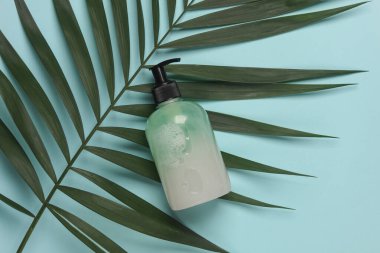 Mavi arkaplanlı ve palmiye yapraklı bir şişe sıvı sabun.