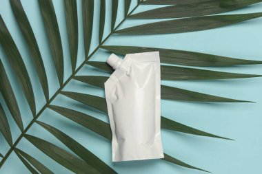 Palmiye yaprağıyla mavi arka planda beyaz Doypack