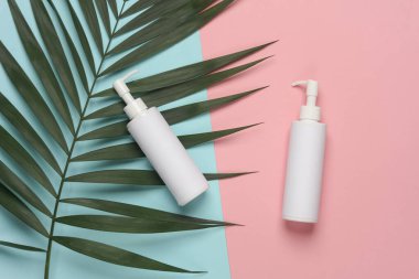 Palmiye yaprağıyla mavi-pembe arkaplanlı şeker şişeleri.