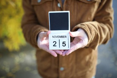 25 Kasım 'da sarı sonbahar yaprakları üzerinde takvim tutan kadın