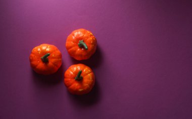 Mor arka planda plastik Cadılar Bayramı balkabakları. Üst görünüm