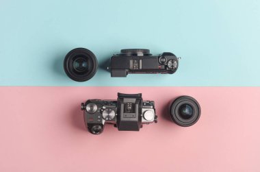 Mavi pembe arka planda lensi olan iki modern aynasız kamera. Üst görünüm