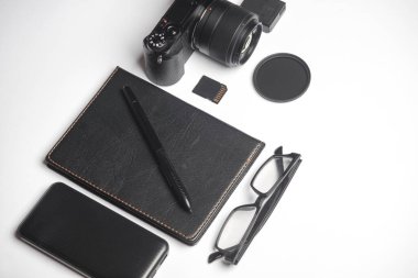 Beyaz arkaplanda kamera, not defteri ve aksesuarları olan yaratıcı bir düzen