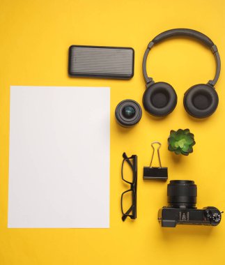 Sarı arkaplan üzerine yazı yazmak için beyaz boş kağıt içeren kamera ve aksesuarlar
