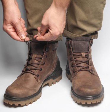 Beyaz arka planda sıcak kış botları giymiş erkek bacakları. Ordu tarzı.