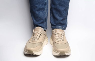 Kotlu erkek bacakları ve beyaz arka planda spor ayakkabıları.