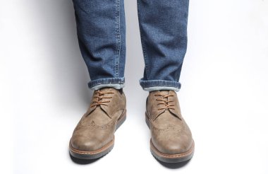 Beyaz arka planda deri ayakkabılı erkek bacakları.