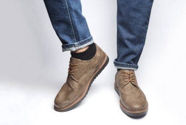 Beyaz arka planda deri ayakkabılı erkek bacakları.