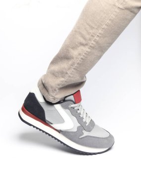 Beyaz arka planda spor ayakkabılı bir erkek bacak.