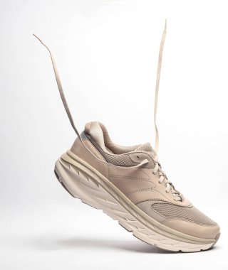 Beyaz arka planda uçan bağcıklı spor ayakkabısı.