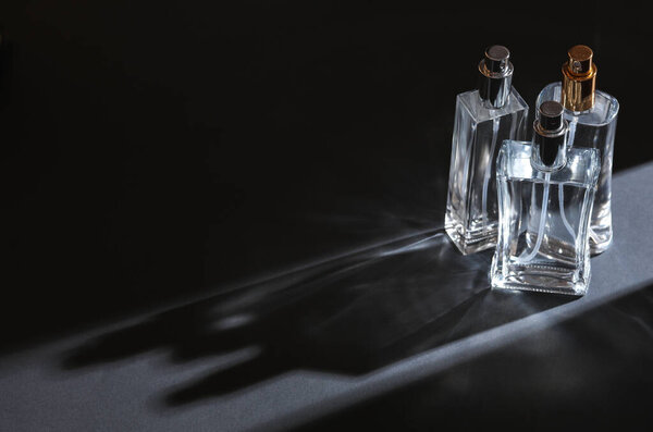 Perfume bottles on gray background with stripe of light and shadow. Minimalism. Beauty Concept photo