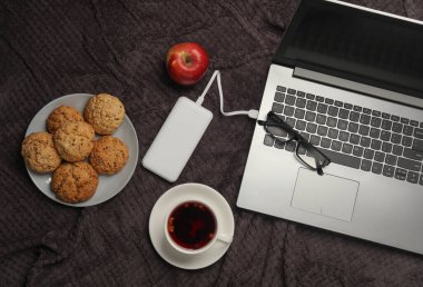 Güç bankası olan dizüstü bilgisayar ve yatakta kahvaltı. Üst görünüm