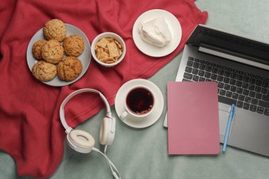 Dizüstü bilgisayar, kulaklık ve yatakta kahvaltı. Üst görünüm