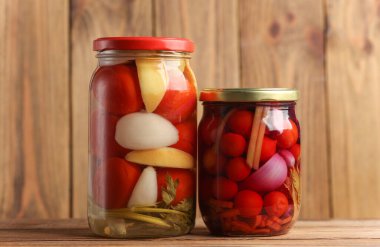 Ahşap yüzeyde cam kavanozlarda salamura domates konservesi. 