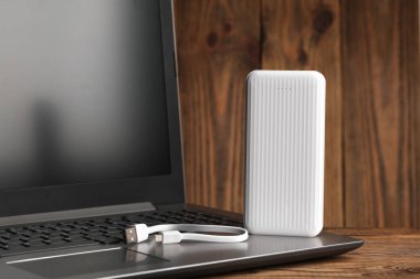 Tahta arka planda güç bankası dış bataryası olan dizüstü bilgisayar