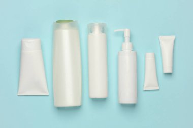 Mavi arka planda kozmetik tüpleri, şişeler ve kavanozlar