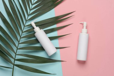 Palmiye yaprağıyla mavi-pembe arkaplanlı şeker şişeleri.