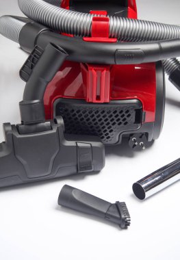 Beyaz arkaplanda eklentileri olan kırmızı elektrikli süpürge