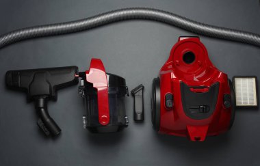 Karanlık arka planda modern bir elektrik süpürgesinin bileşenleri ve ekleri. Üst Manzara. Düz yatıyordu