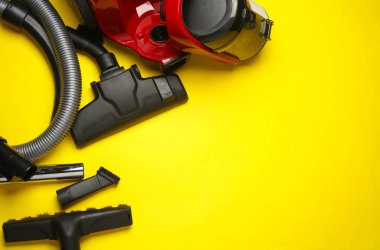 Sarı arka planda modern bir elektrik süpürgesinin bileşenleri ve eklentileri. Üst Manzara. Düz yatıyordu