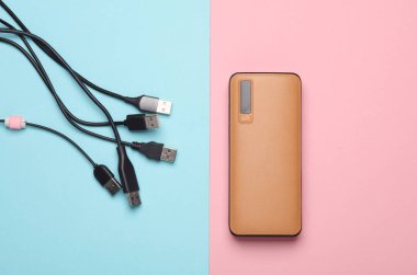 Pembe mavi arka planda birçok usb kablosu olan dış batarya güç bankası
